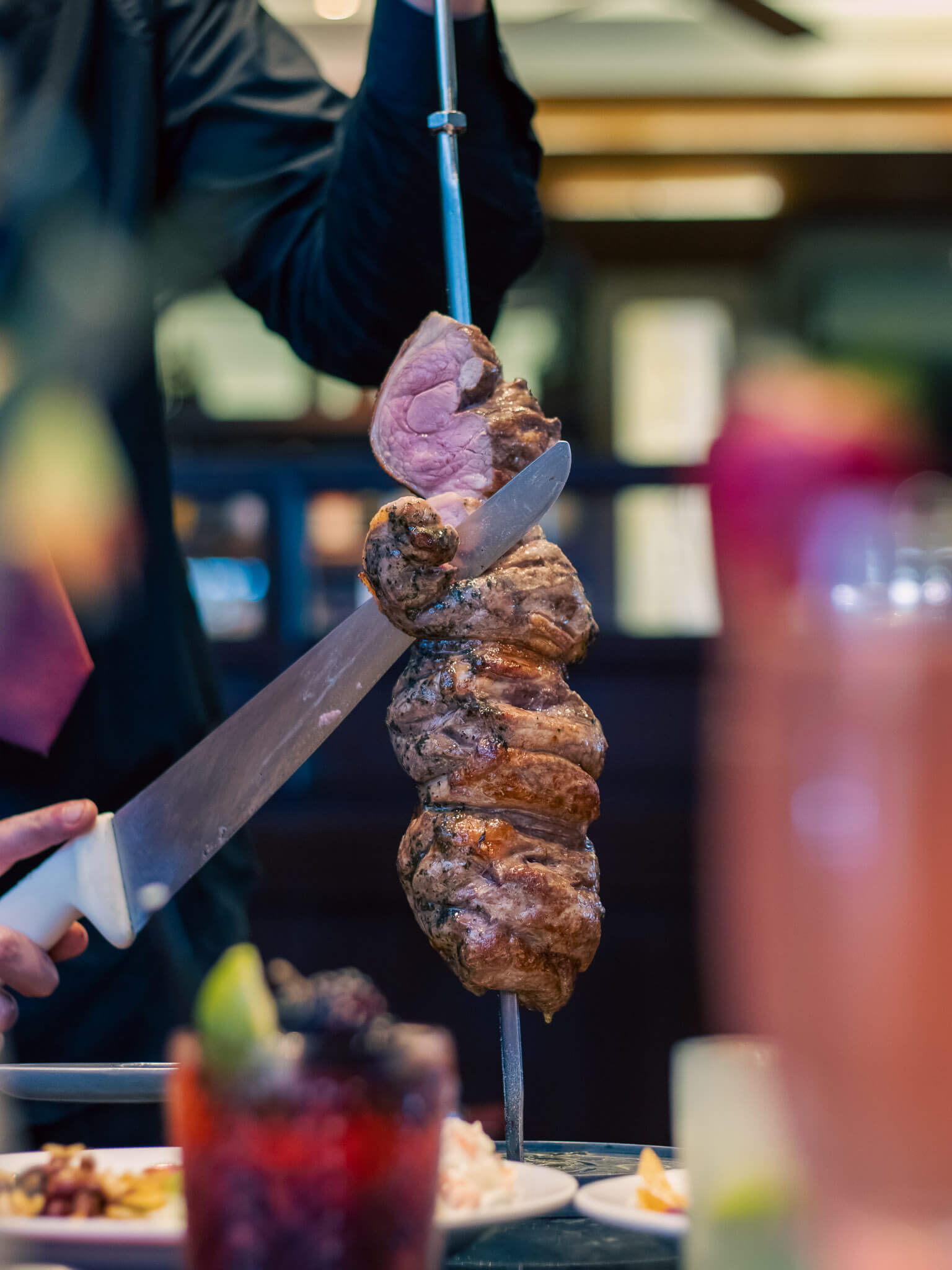 Waiter carving meat off a skewer